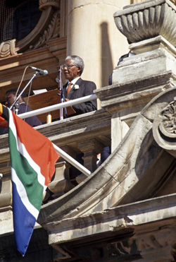 After the elections in 1994: Newly-elected President Nelson Mandela addressing the crowd from a balcony of the Townhall. UN Photo/Chris Sattlberger.