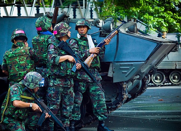 Soldiers of the Royal Thai Army take cover next to a Type-85 AFV near the Red Shirt barricade at Chulalongkorn Hospital.